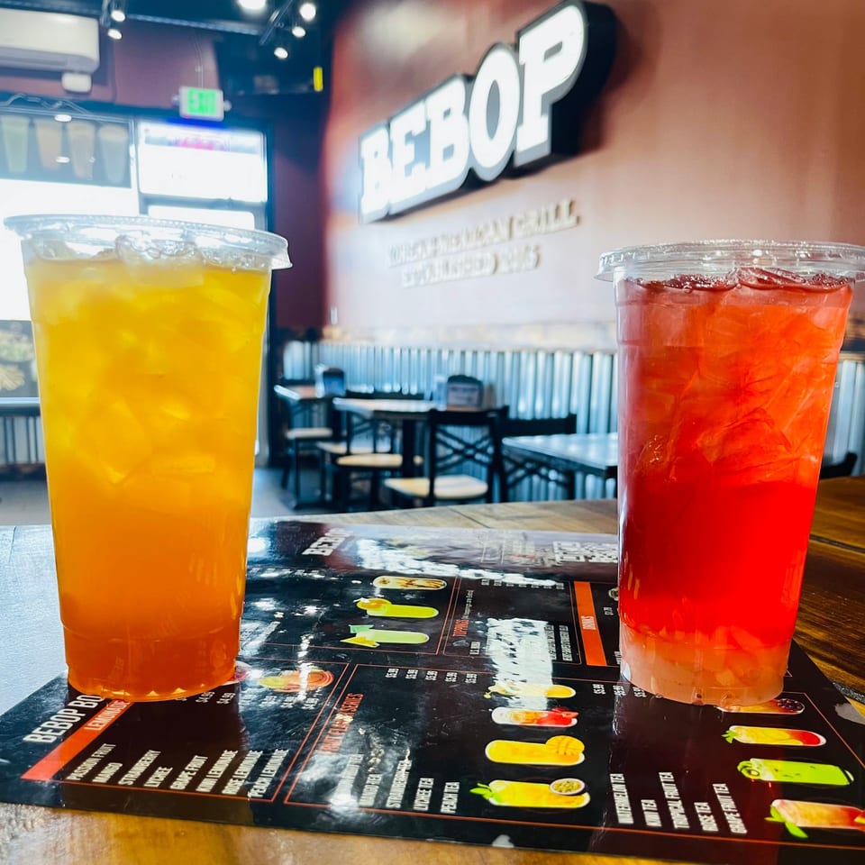 Two colorful iced drinks, orange and red, on a menu at Bebop Korean Mexican Grill.